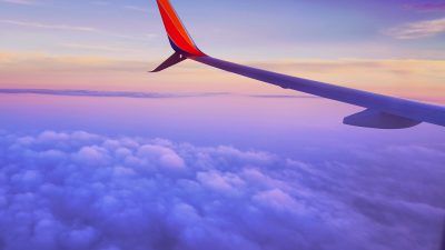 person in a plane flying at high altitude taking photo of left airplane wing during daytime
